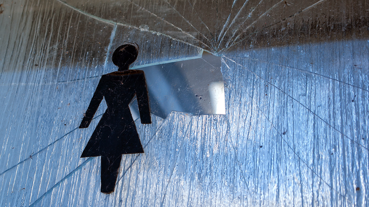 Domestic violence against women - symbolic image of broken glass and a woman sign.