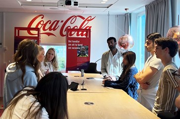 Students around a smaller conference table talking to representatives from Coca-Cola Europacific Partners.