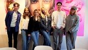 Group of students smiling in front of a larger artwork at an H&M office